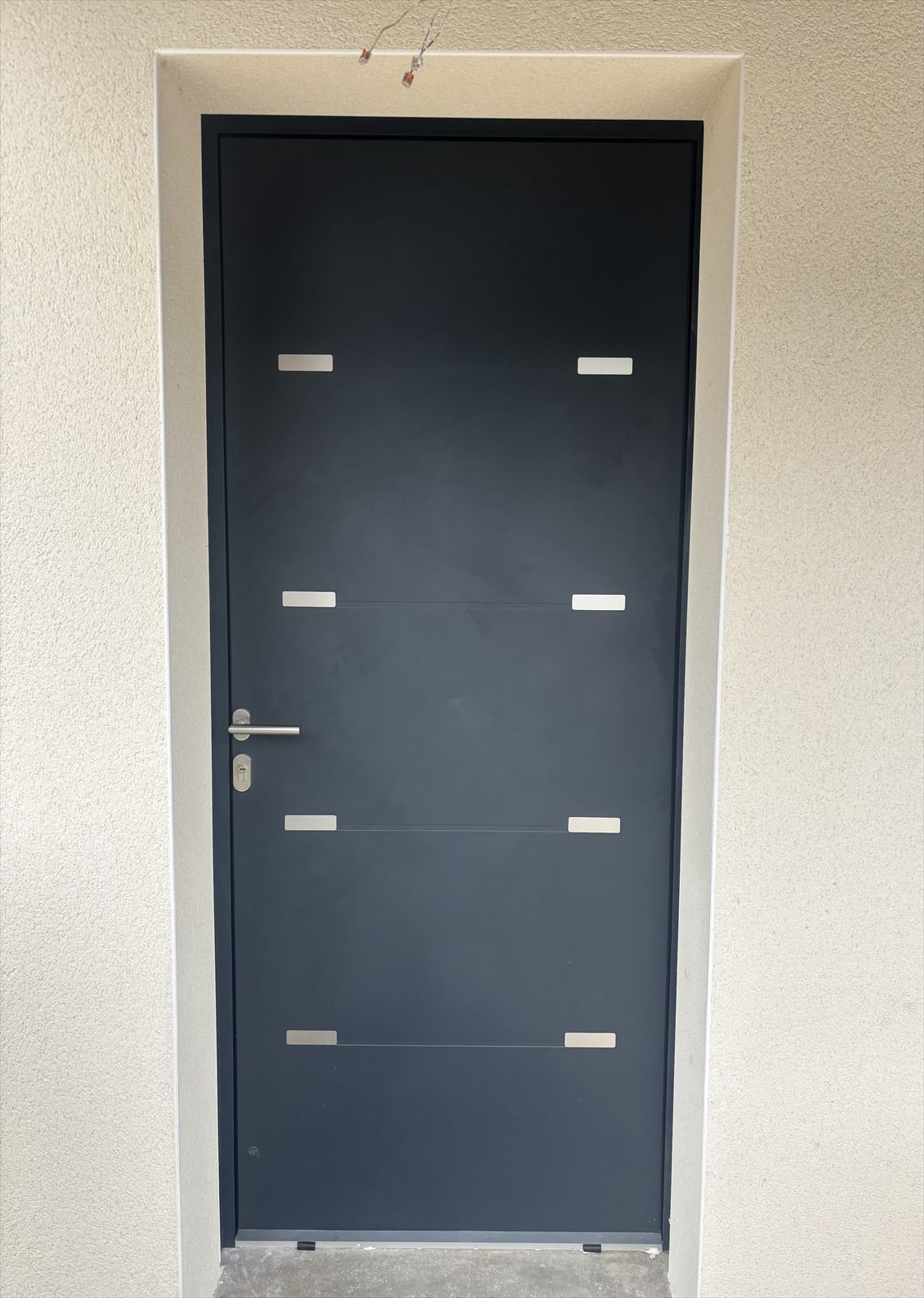 Porte d'entrée contemporaine gris anthracite posée sur une maison en rénovation